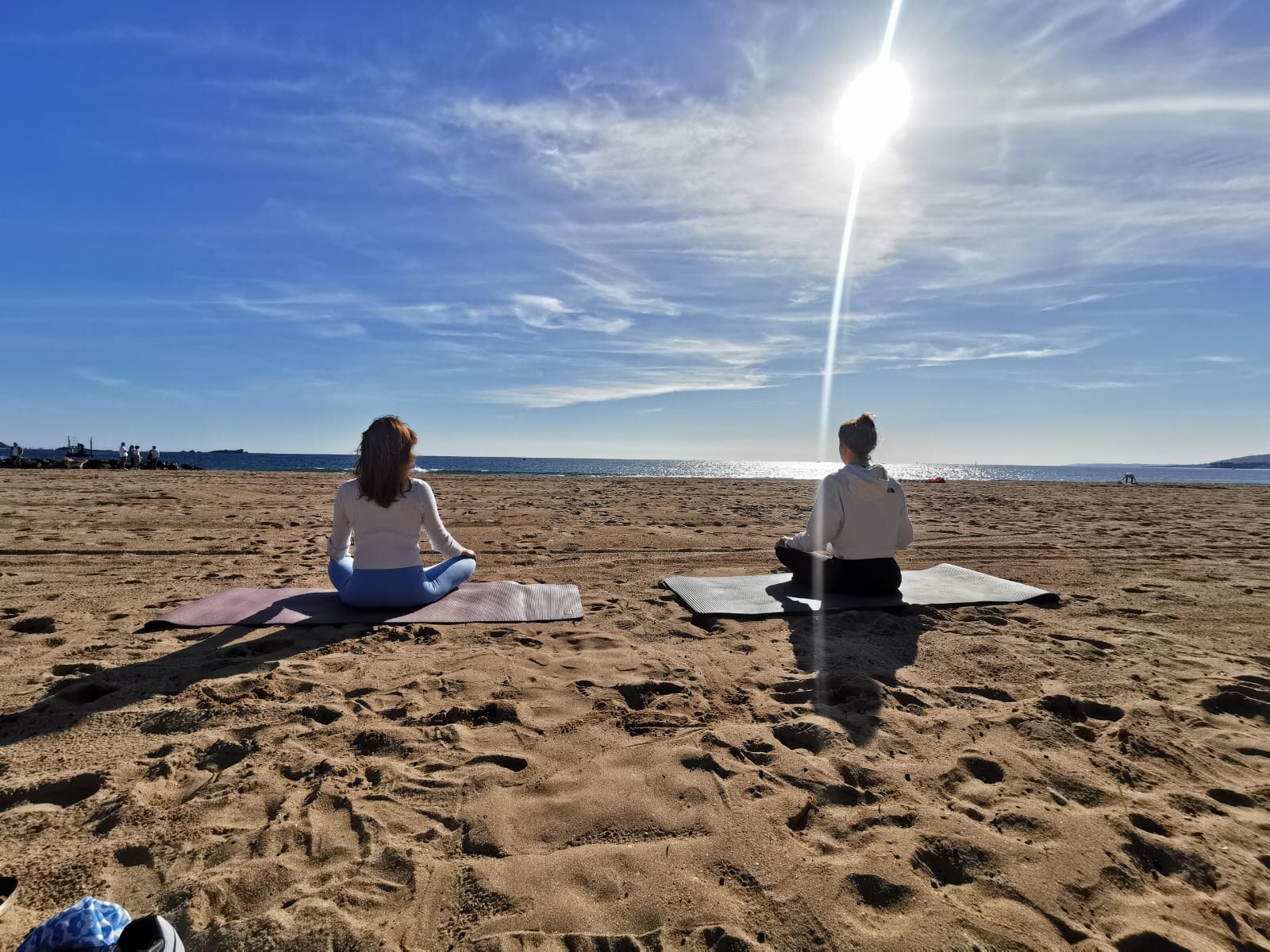 Deux personnes en méditation face à la mer sur une plage des Issambres